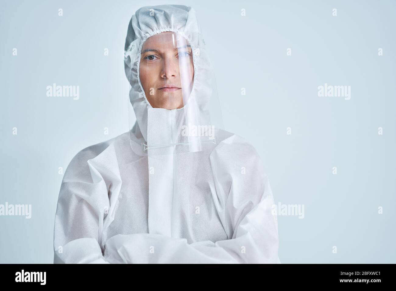 Donna in tuta a rischio biologico e visiera su sfondo bianco. Foto Stock