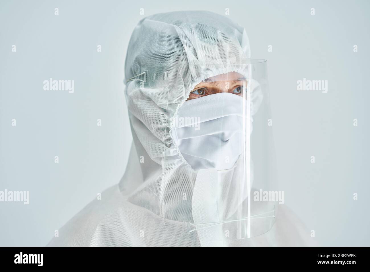 Donna in tuta a rischio biologico e visiera su sfondo bianco. Foto Stock