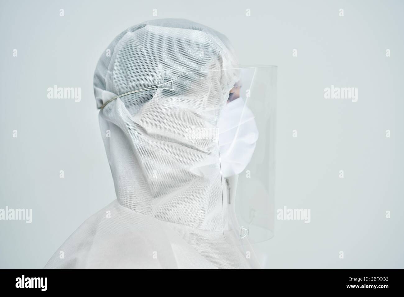 Donna in tuta a rischio biologico e visiera su sfondo bianco. Foto Stock