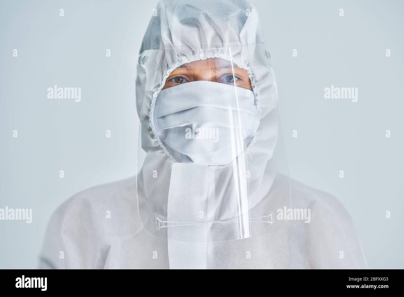 Donna in tuta a rischio biologico e visiera su sfondo bianco. Foto Stock