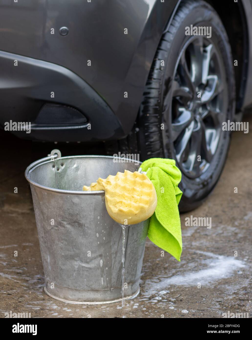 Un secchio con detergente, panno in microfibra e spugna per autolavaggio. Lavando a mano con acqua saponata. Foto Stock