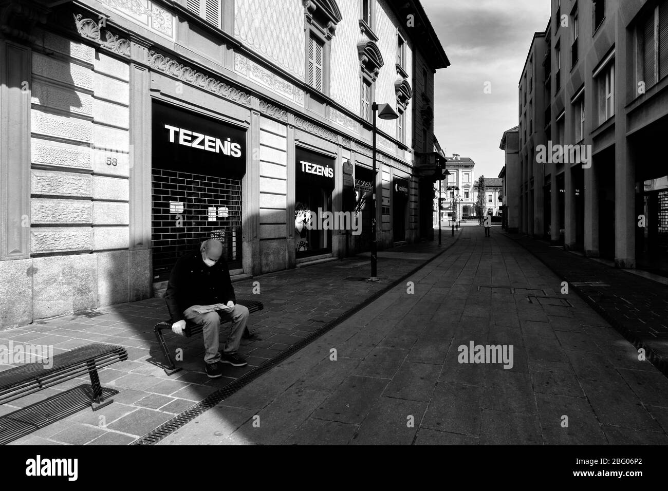 Il silenzio e la desolazione in una città vicino a Milano, domenica mattina, durante Coronavirus. Nella strada principale solo due persone, una a piedi, l'altra Foto Stock
