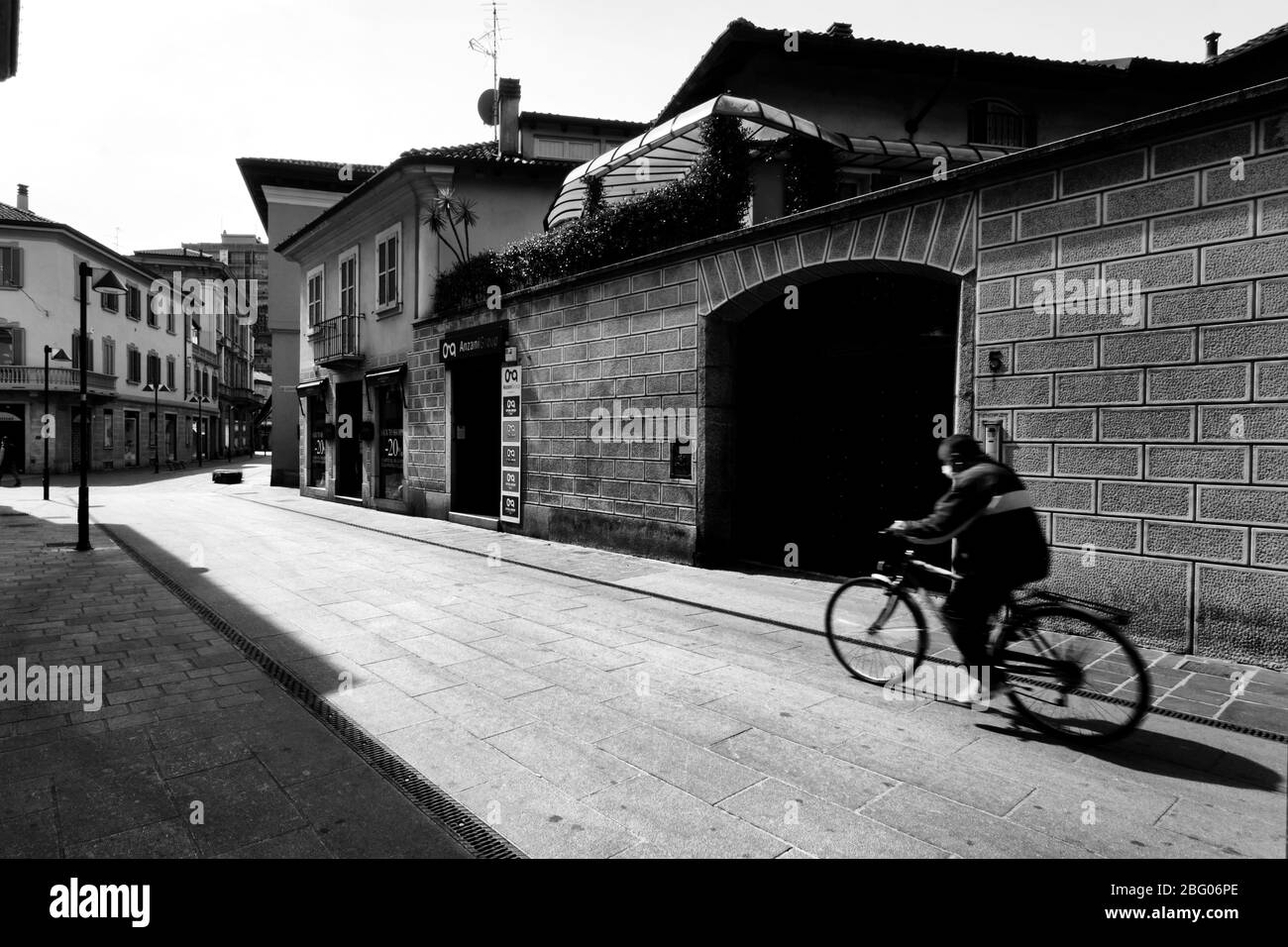 Egli silenzio e la desolazione in una città vicino a Milano, domenica mattina, durante Coronavirus. Nella strada principale del centro città solo un uomo in bicicletta w Foto Stock