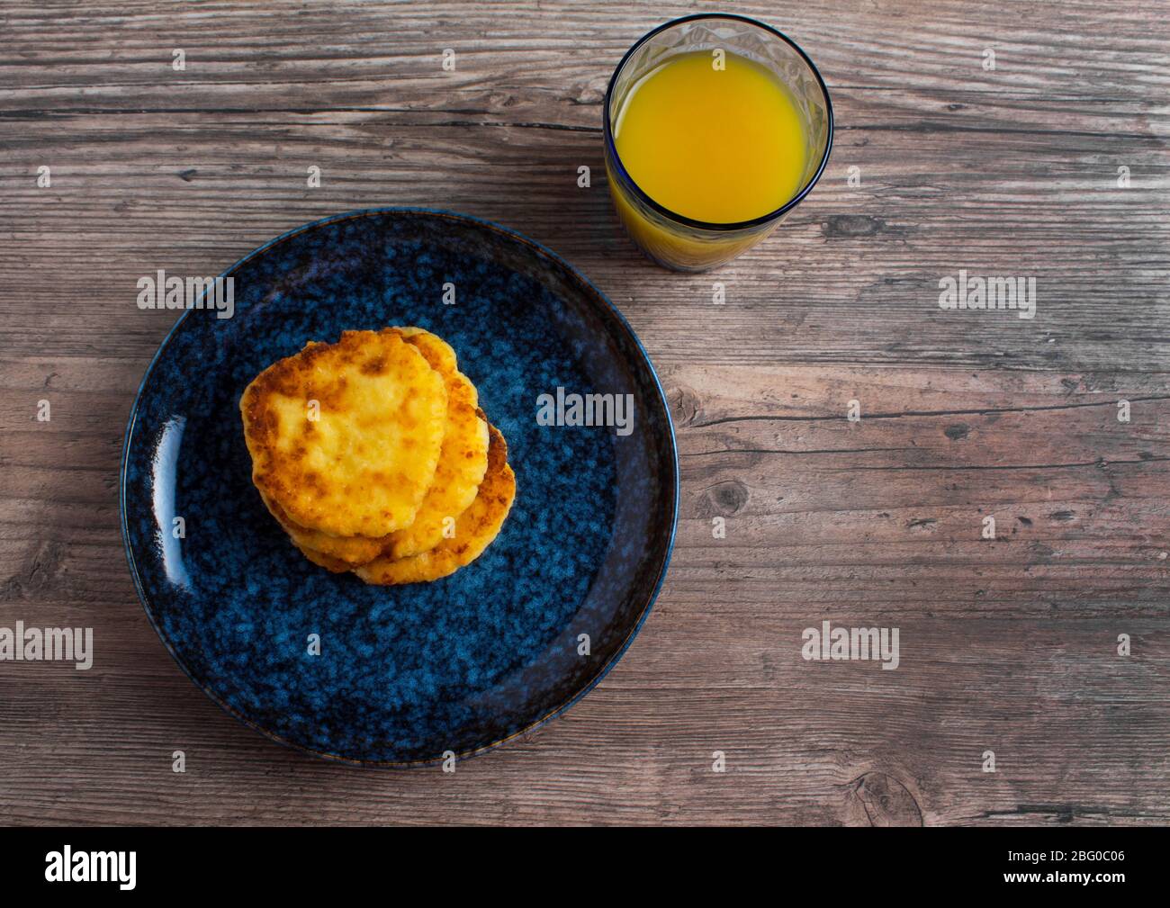 Colazione, cibo. Pancake su un piatto blu e succo d'arancia. Cibo fatto in casa, ricetta semplice. Uno stile di vita sano. Disposizione piatta. Decorazioni di lusso. Foto Stock