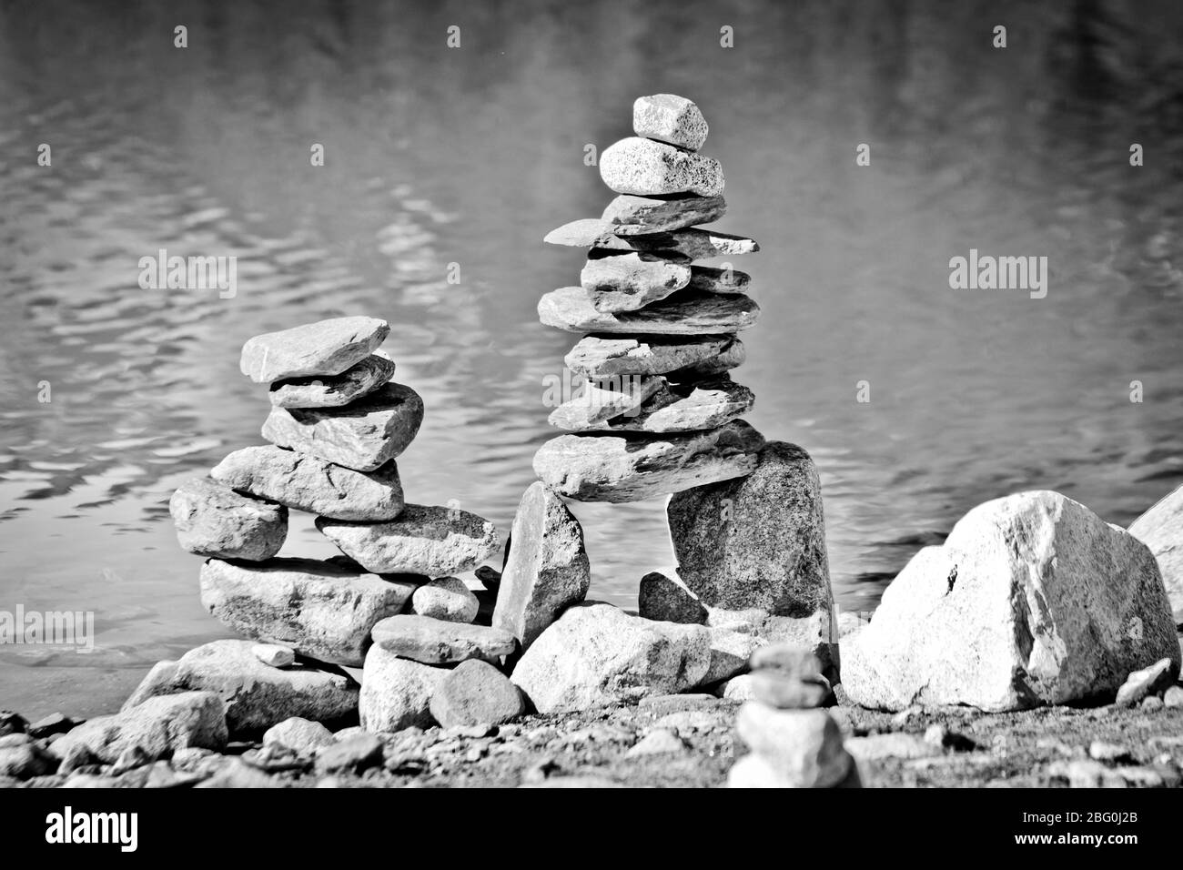 Piramidi di pietra, piccolo uomo, tumulo, ovoo, Inukshuk costruito per la vostra calma e tranquillità fatta vicino al lago o fiume di montagna in bianco e nero Foto Stock