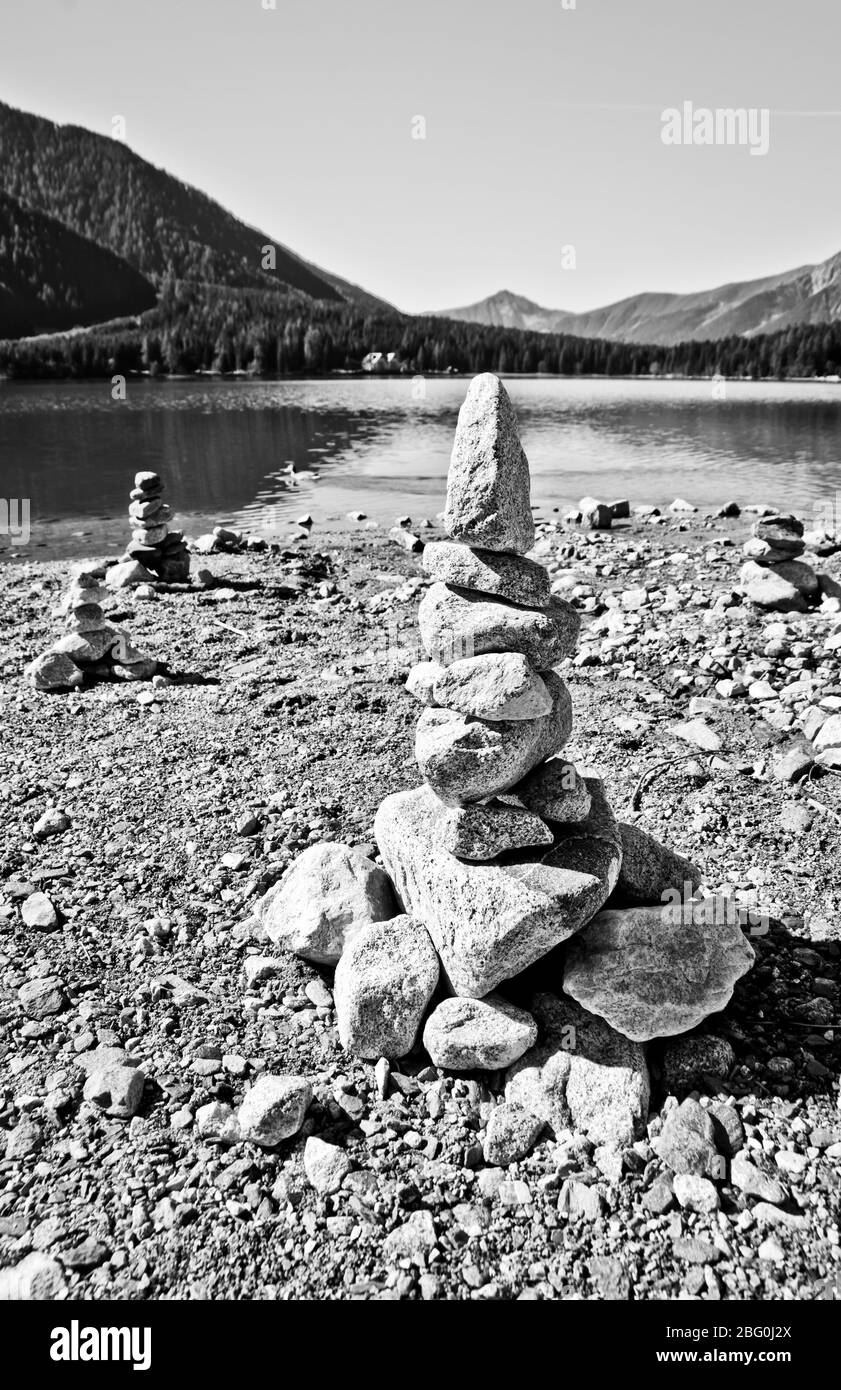 Piramidi di pietra, piccolo uomo, tumulo, ovoo, Inukshuk costruito per la vostra calma e tranquillità fatta vicino al lago o fiume di montagna in bianco e nero Foto Stock