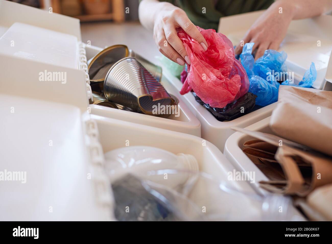 Primo piano di donna irriconoscibile mettere sacchetto di plastica scartato nel cestino mentre smistamento rifiuti a casa, copia spazio Foto Stock