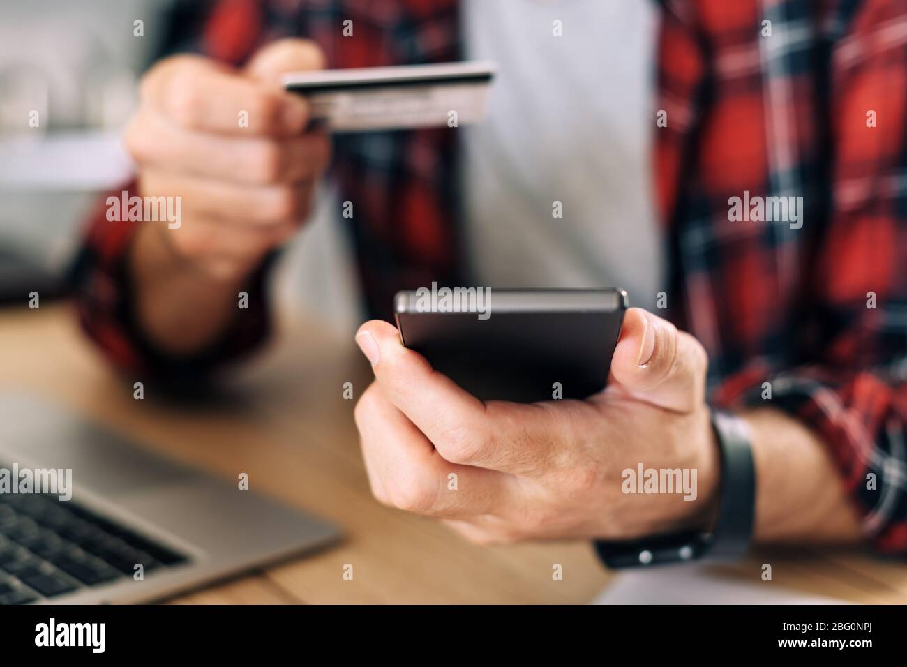 Shopping online dall'ufficio domestico utilizzando smartphone e carta di credito, primo piano di mani maschili in concetto di e-commerce Foto Stock