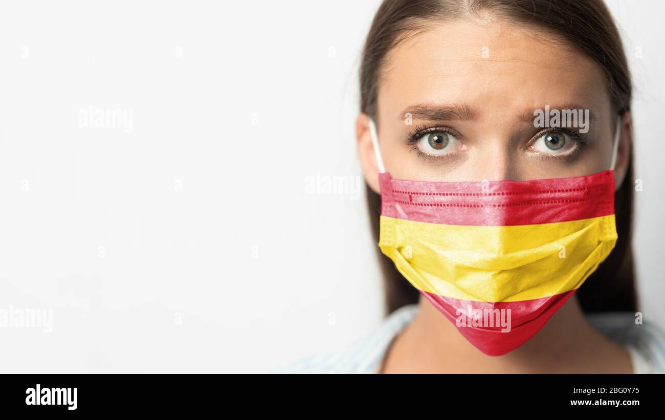 Donna che indossa maschera protettiva con bandiera spagnola su sfondo bianco Foto Stock