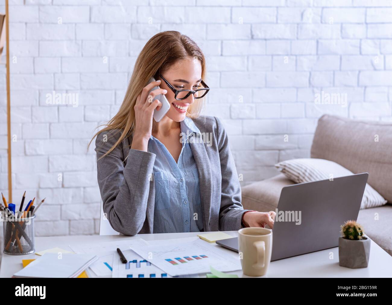 Wwoman che parla al telefono e guarda il notebook Foto Stock