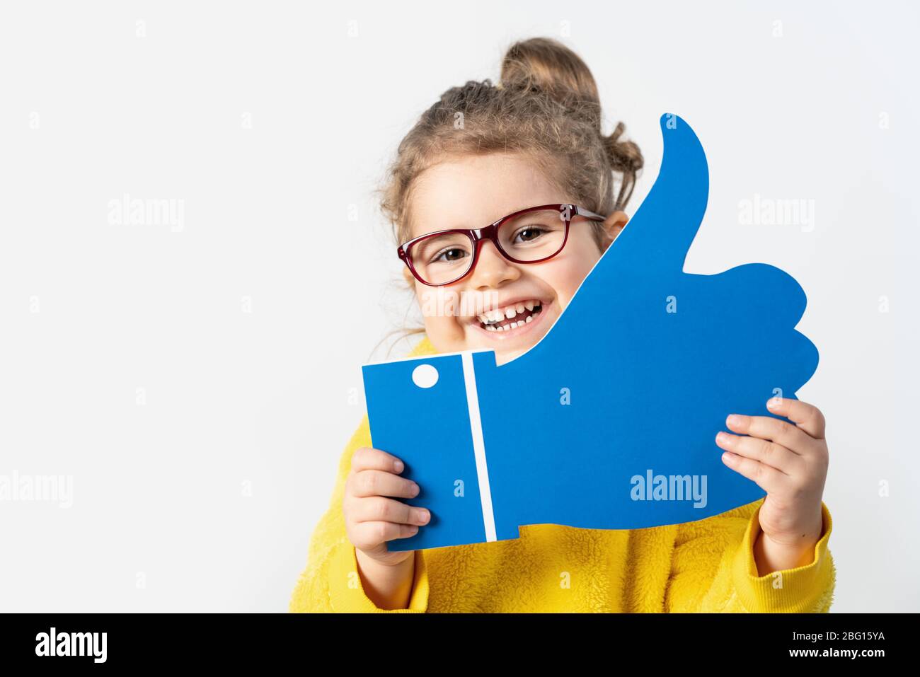 Adorabile bambina sta tenendo un cartone con il segno simile, isolato su sfondo bianco Foto Stock
