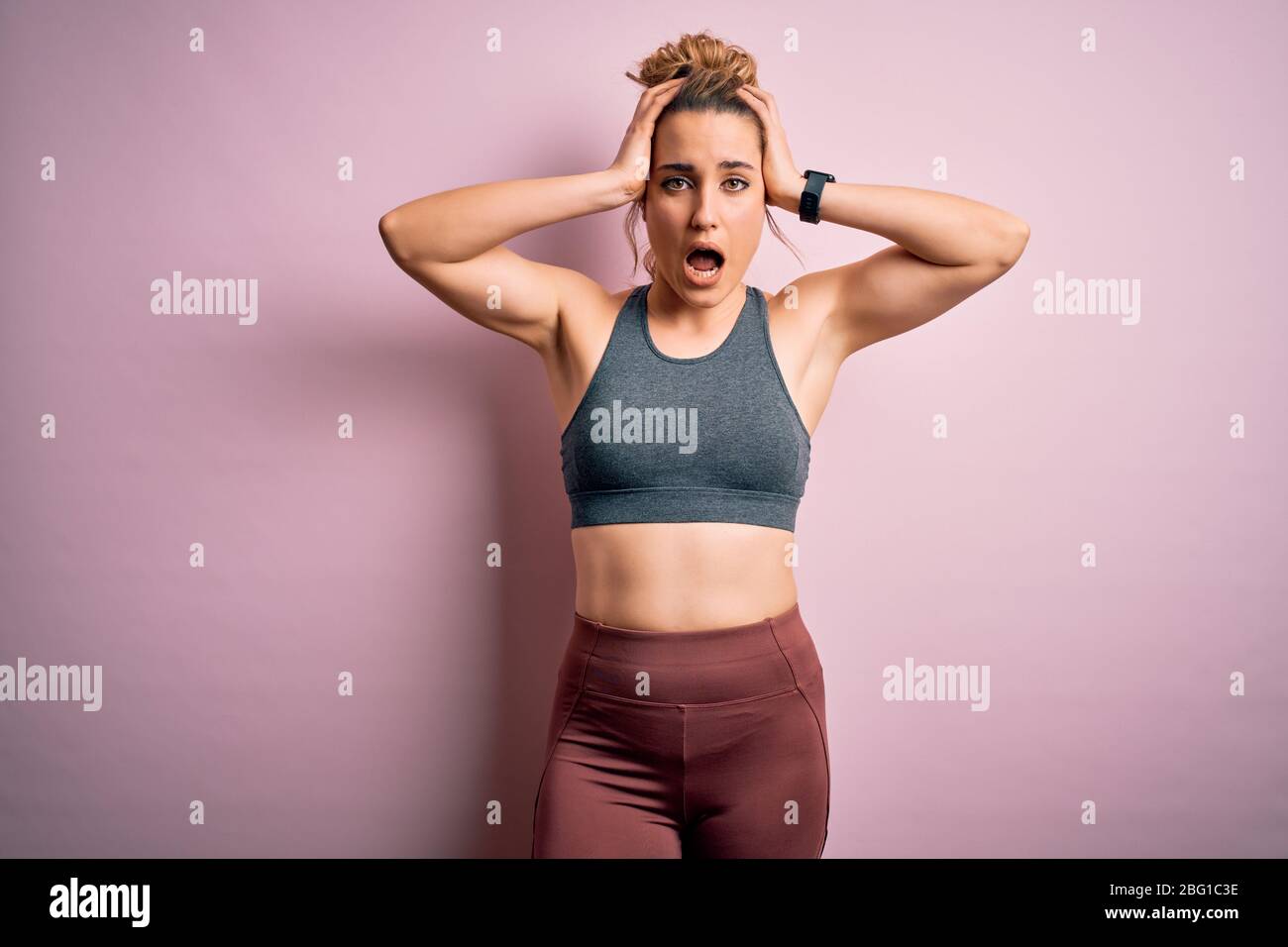 Giovane bella bionda sportivo donna che fa sport indossare abbigliamento  sportivo su sfondo rosa Crazy e spaventato con le mani sulla testa,  impaurito e sorpreso di sh Foto stock - Alamy