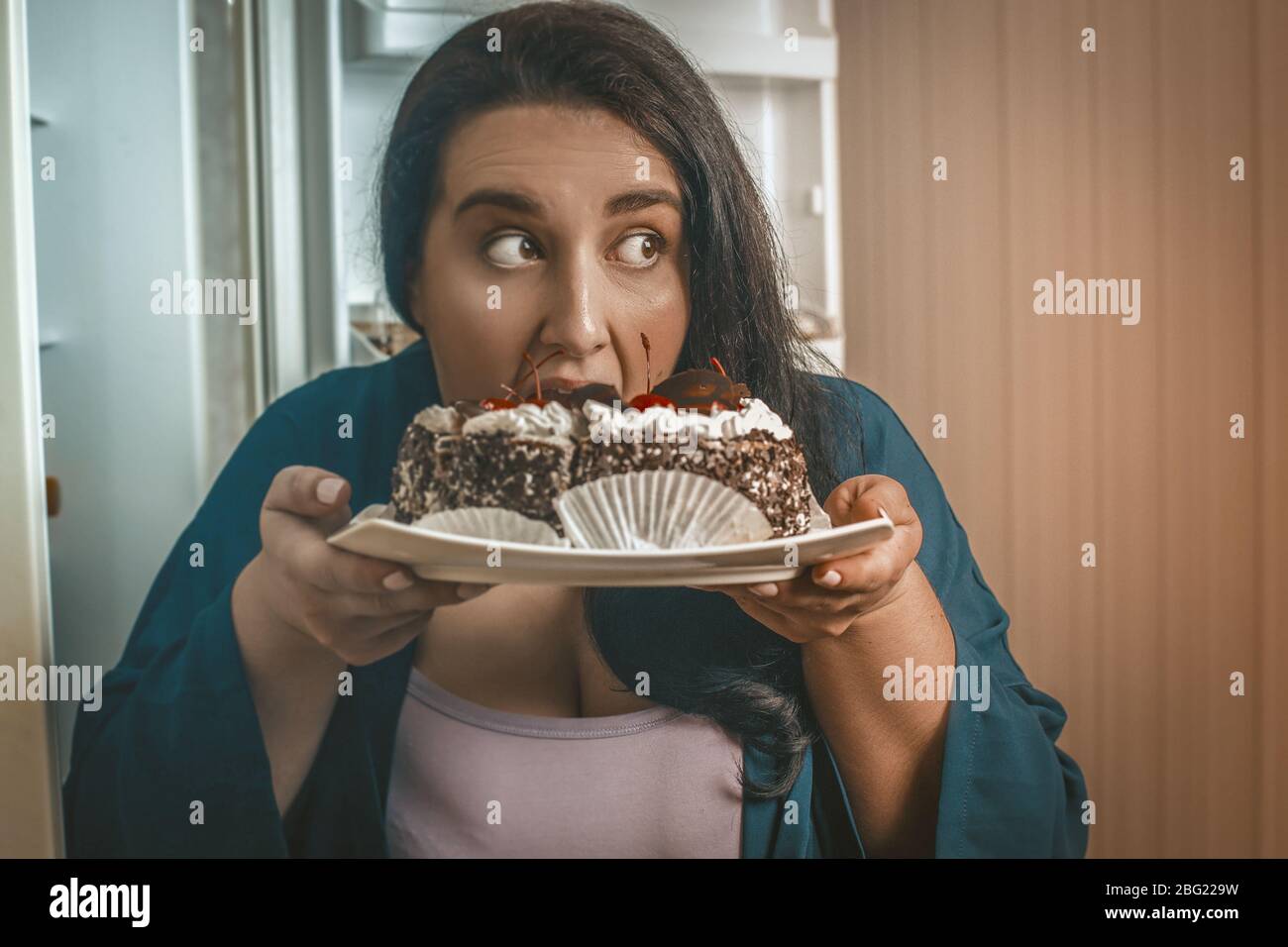Corpo positivo Donna mangiare cioccolato Dessert in cucina Foto Stock