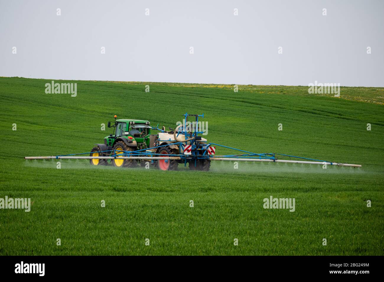 Trattore con irroratrice trainata applicare erbicidi, pesticidi o fertilizzanti su colture agricole Foto Stock