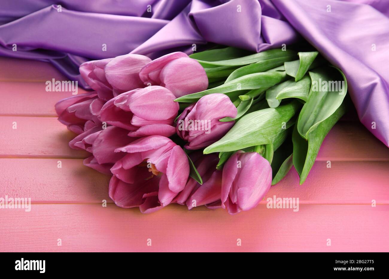 Bel bouquet di tulipani viola su sfondo di legno rosa Foto Stock