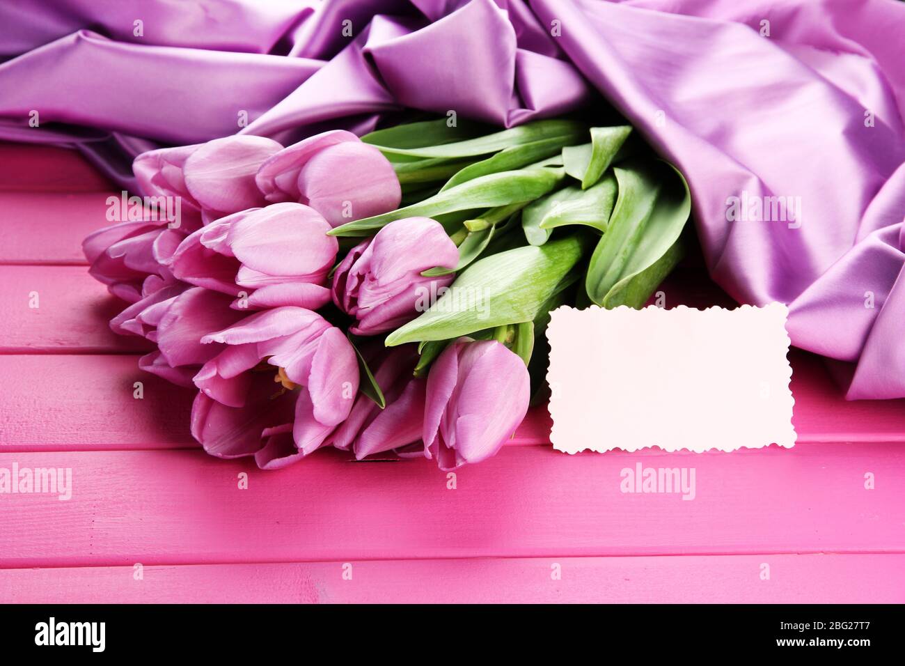 Bel bouquet di tulipani viola su sfondo di legno rosa Foto Stock