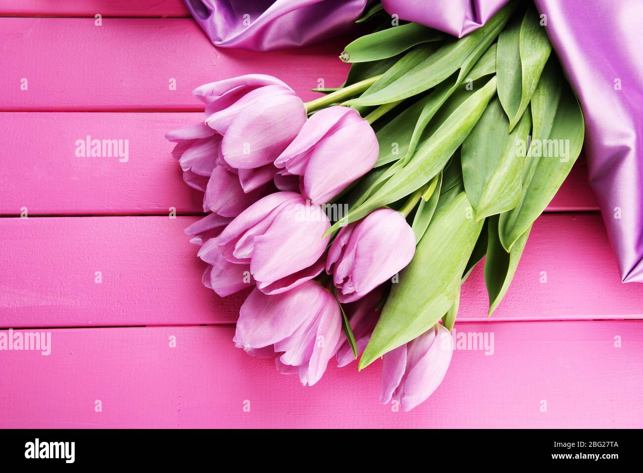 Bel bouquet di tulipani viola su sfondo di legno rosa Foto Stock