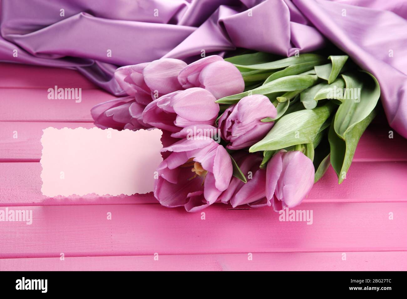 Bel bouquet di tulipani viola su sfondo di legno rosa Foto Stock