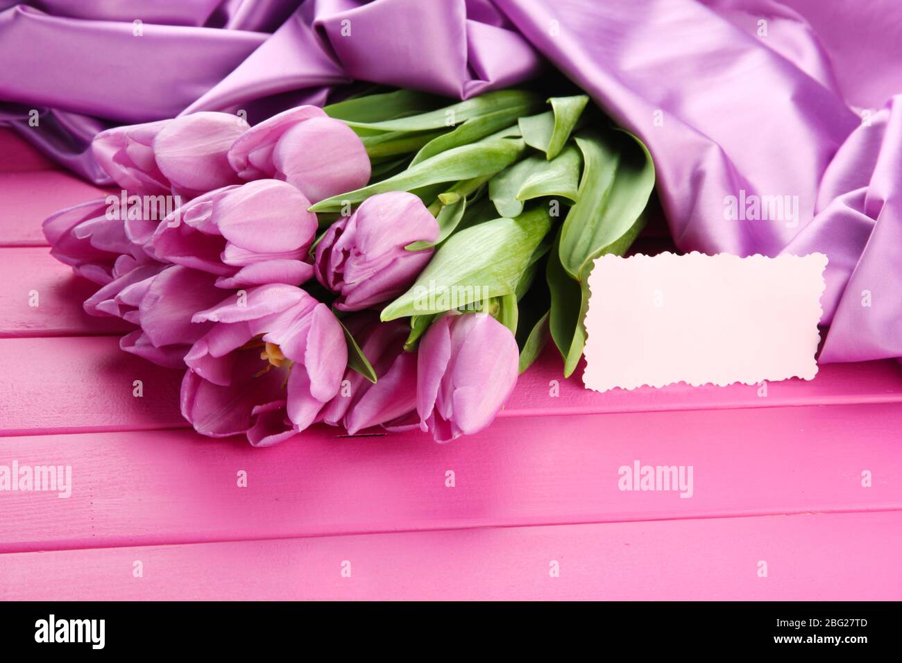 Bel bouquet di tulipani viola su sfondo di legno rosa Foto Stock
