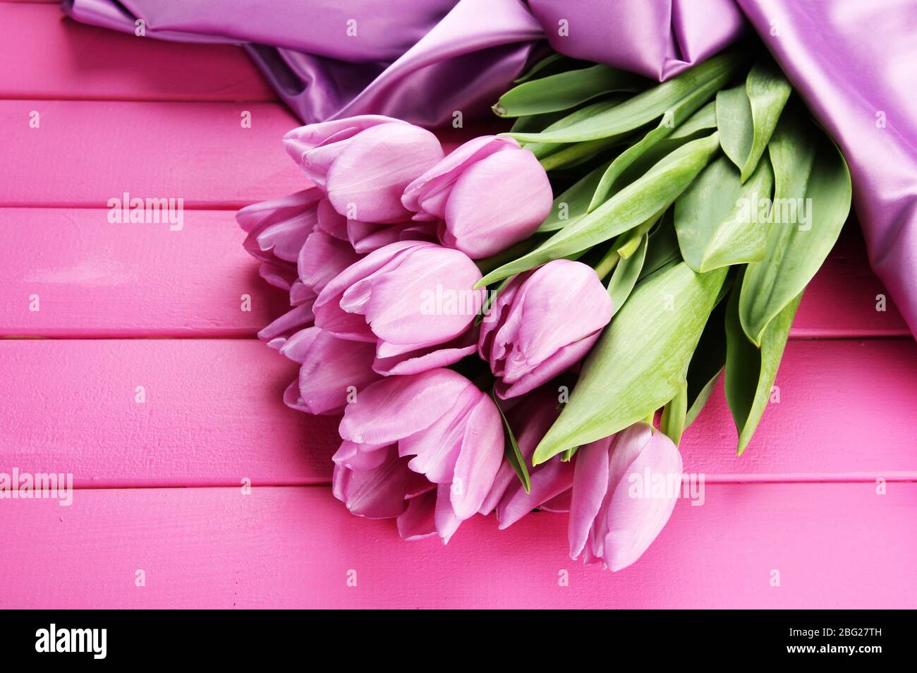 Bel bouquet di tulipani viola su sfondo di legno rosa Foto Stock