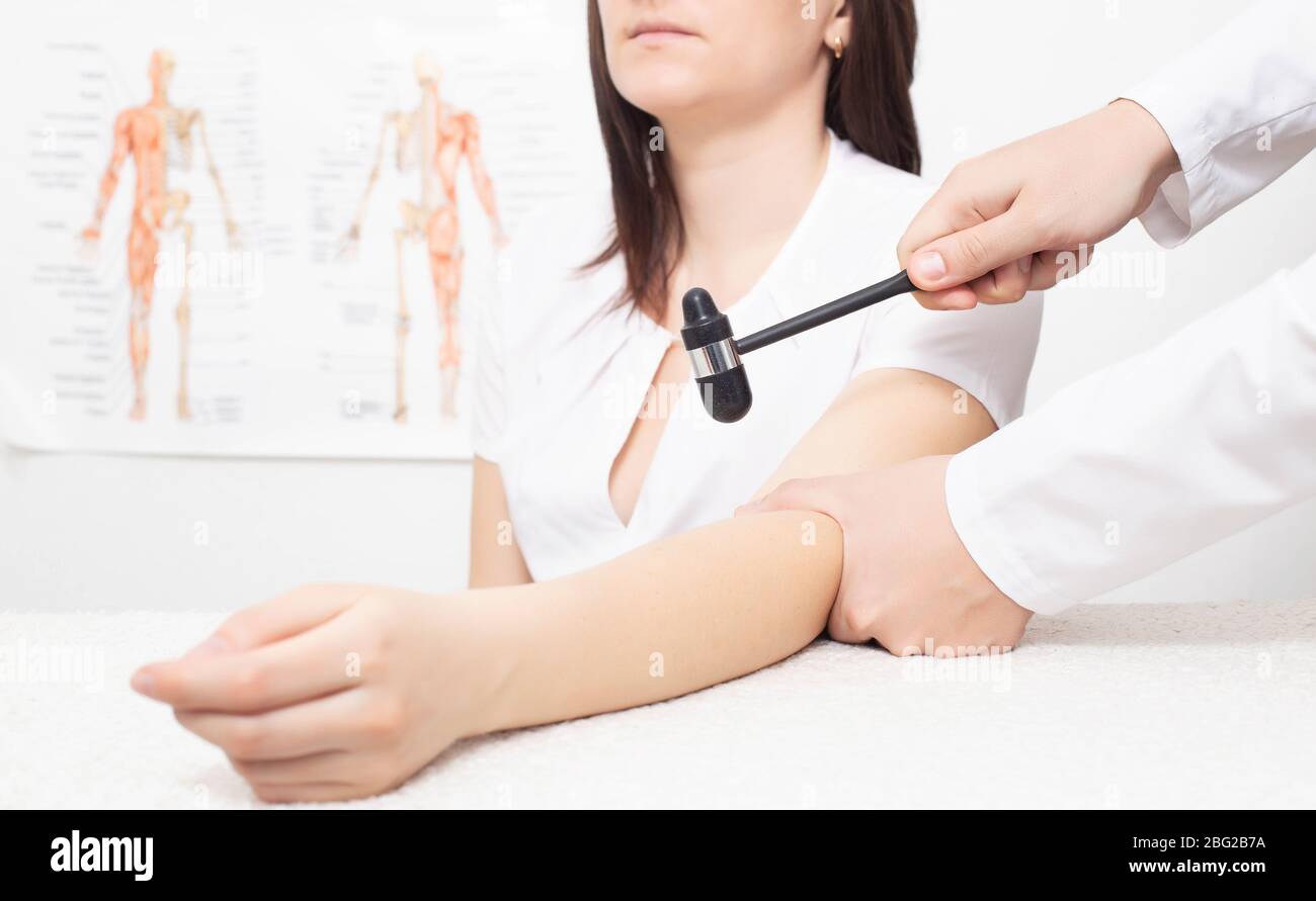 Un medico neurologo controlla il riflesso bicipite in una paziente ragazza  con un martello neurologico Foto stock - Alamy