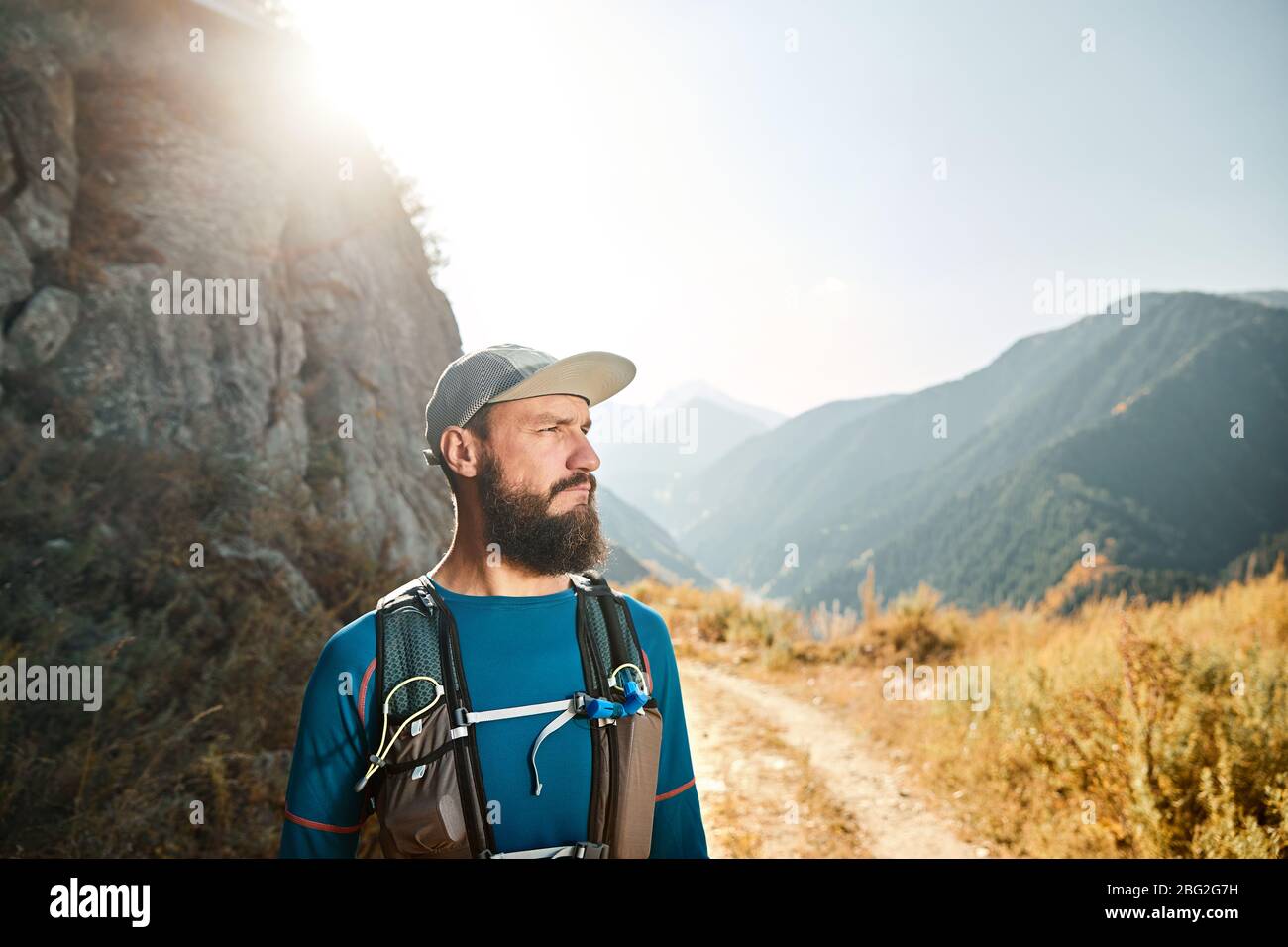 Ritratto di barbuto atleta runner con zaino in montagna a sunrise Foto Stock
