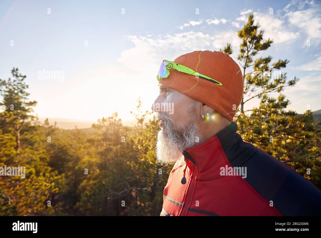 Ritratto di vecchio con barba bianca in camicia rossa e nella foresta al tramonto Foto Stock