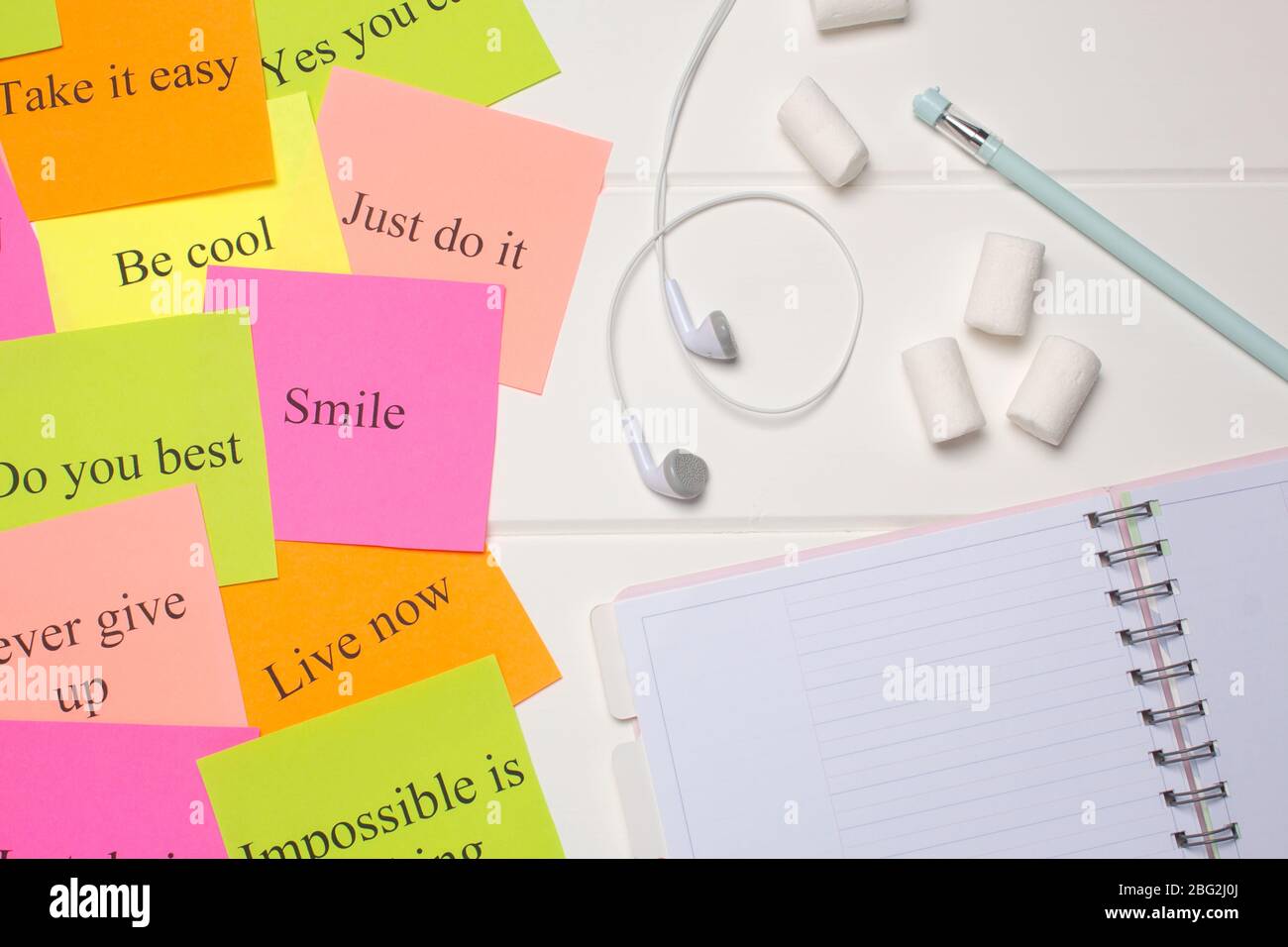 Pianificatore giornaliero, penna, cuffie e cartoline colorate. Primo piano su sfondo bianco. Spazio di copia. Foglio pulito, disposizione piatta, vista dall'alto. Elenco attività, mar Foto Stock
