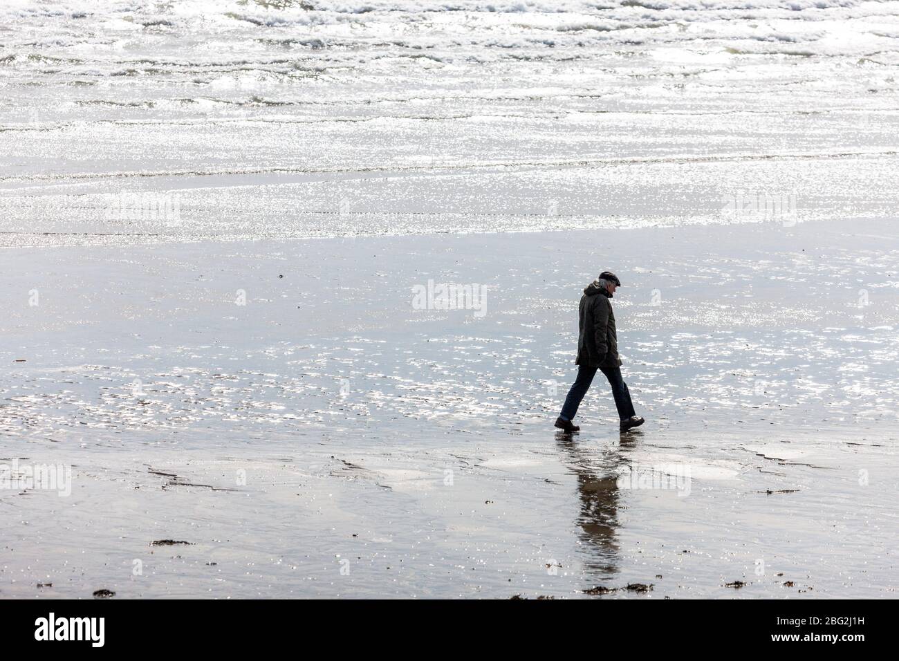 Fountainstown, Cork, Irlanda. 20 aprile 2020. Un anziano cammina sollone sulla spiaggia di Fountainstown, Co. Cork, Irlanda. Secondo le restrizioni di Covid-19, le persone possono fare stregoni solo entro 2 km dalla loro casa. - credito; David Creedon / Alamy Live News Foto Stock