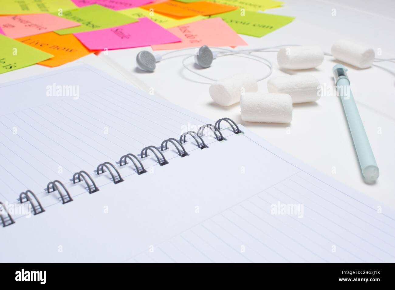 Pianificatore giornaliero, penna, cuffie e cartoline colorate. Primo piano su sfondo bianco. Spazio di copia. Pulire il foglio. Elenco delle attività, marshmallow. Foglio colore Foto Stock