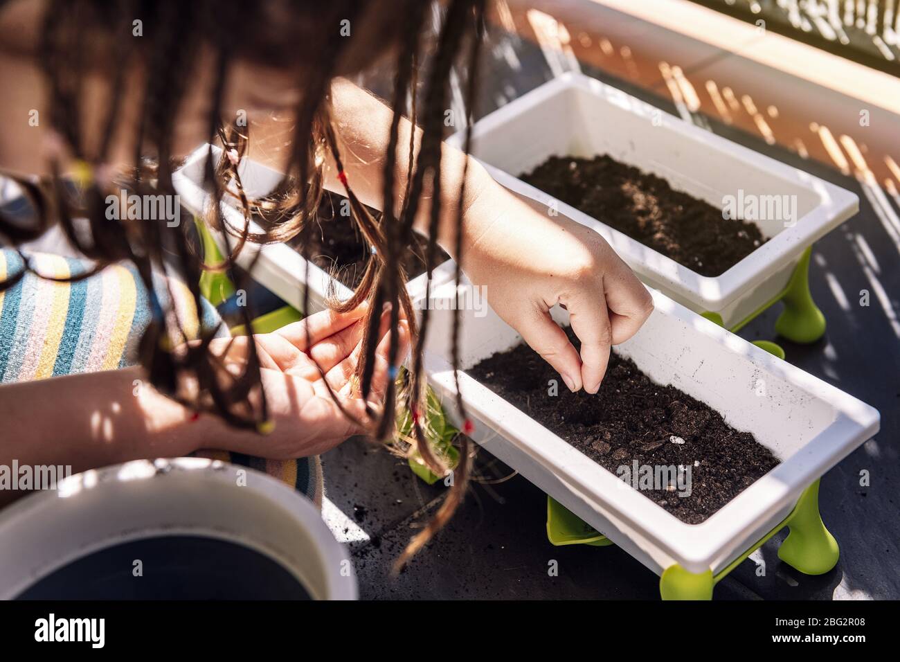 primo piano di una ragazza che mette i semi nella sporcizia dei vasi di fiori al balcone, hobby a casa, sostenibile ed ecologico stile di vita concetto Foto Stock