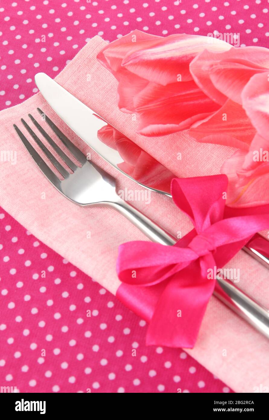 Un ambiente da pranzo festoso con tulipani su sfondo rosa polka-dot Foto Stock