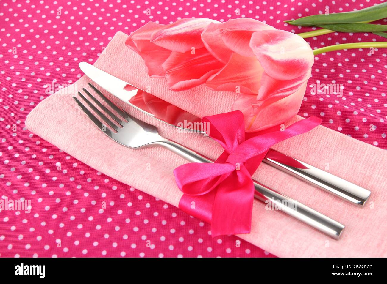 Un ambiente da pranzo festoso con tulipani su sfondo rosa polka-dot Foto Stock