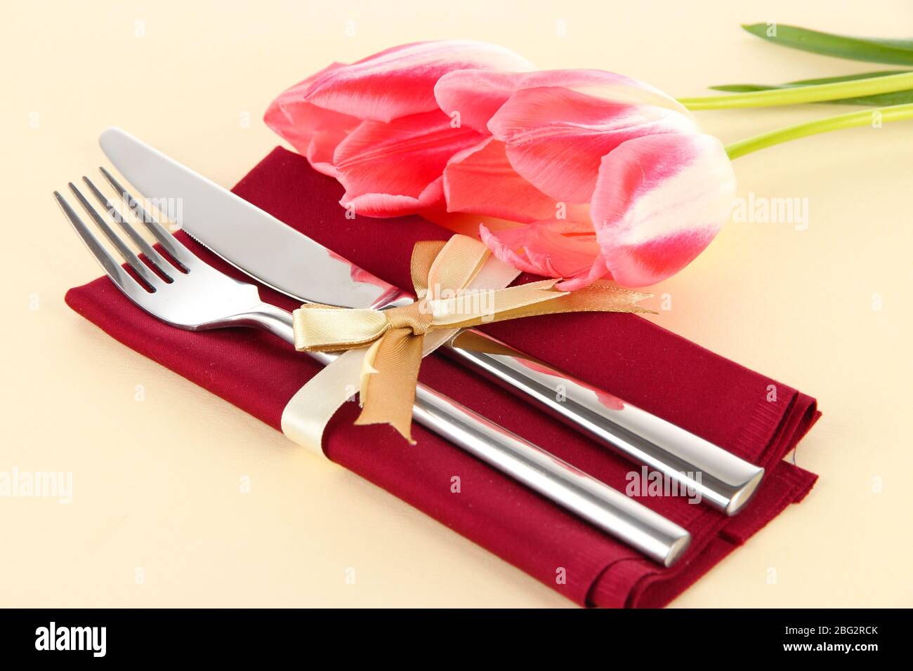 Ambiente da pranzo festoso con tulipani su sfondo beige Foto Stock