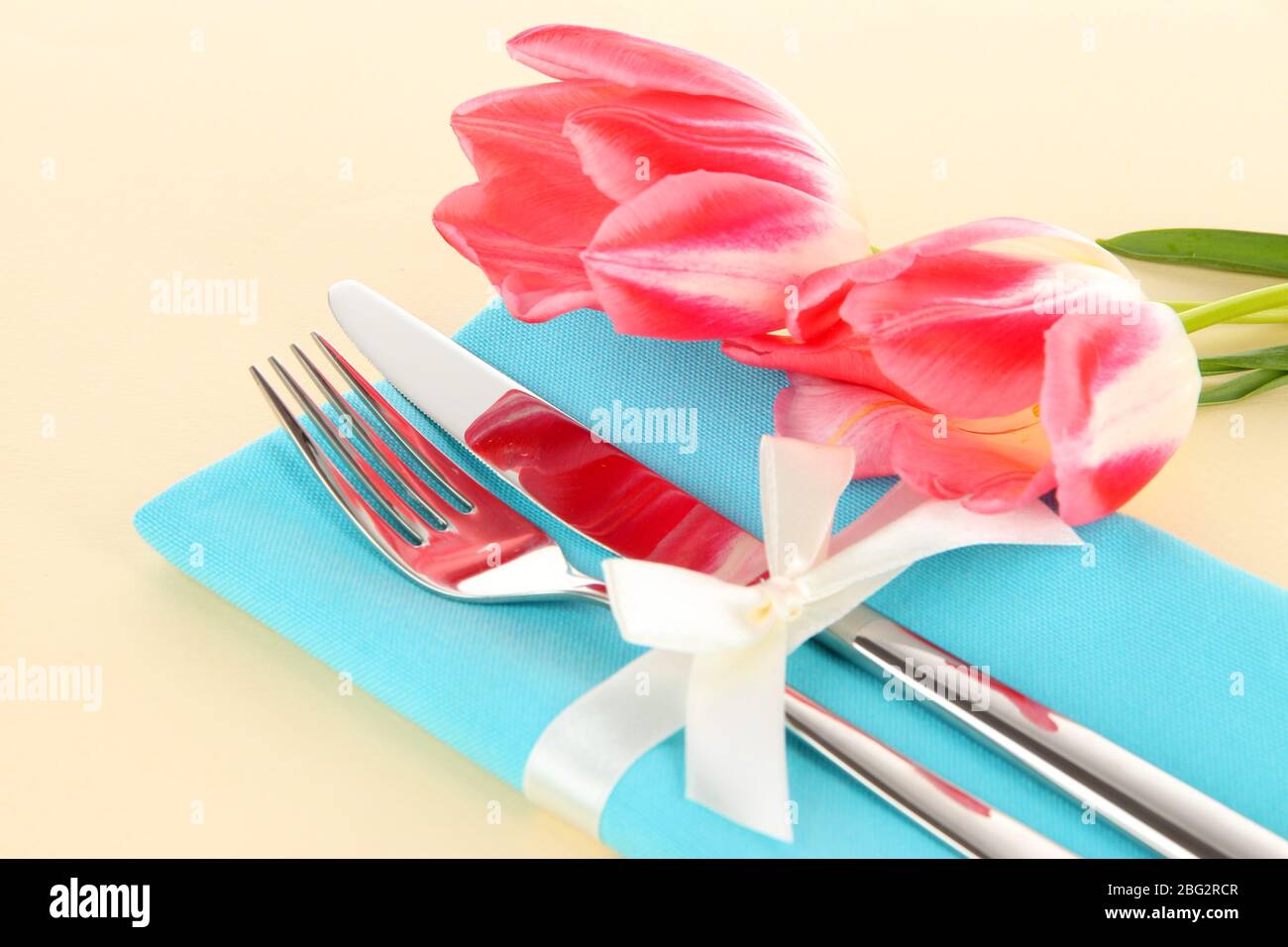Ambiente da pranzo festoso con tulipani su sfondo beige Foto Stock