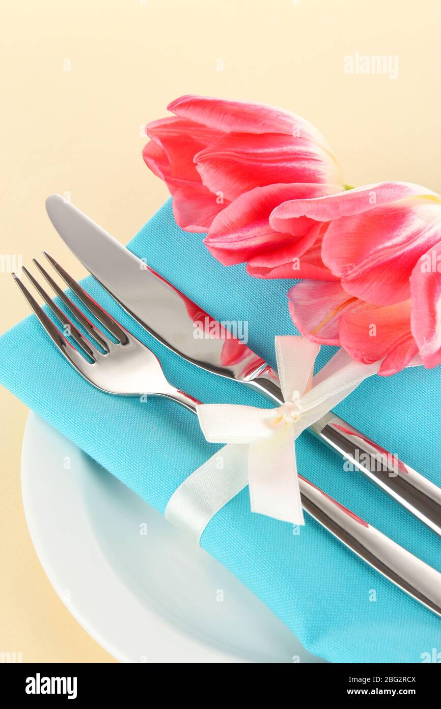 Ambiente da pranzo festoso con tulipani su sfondo beige Foto Stock