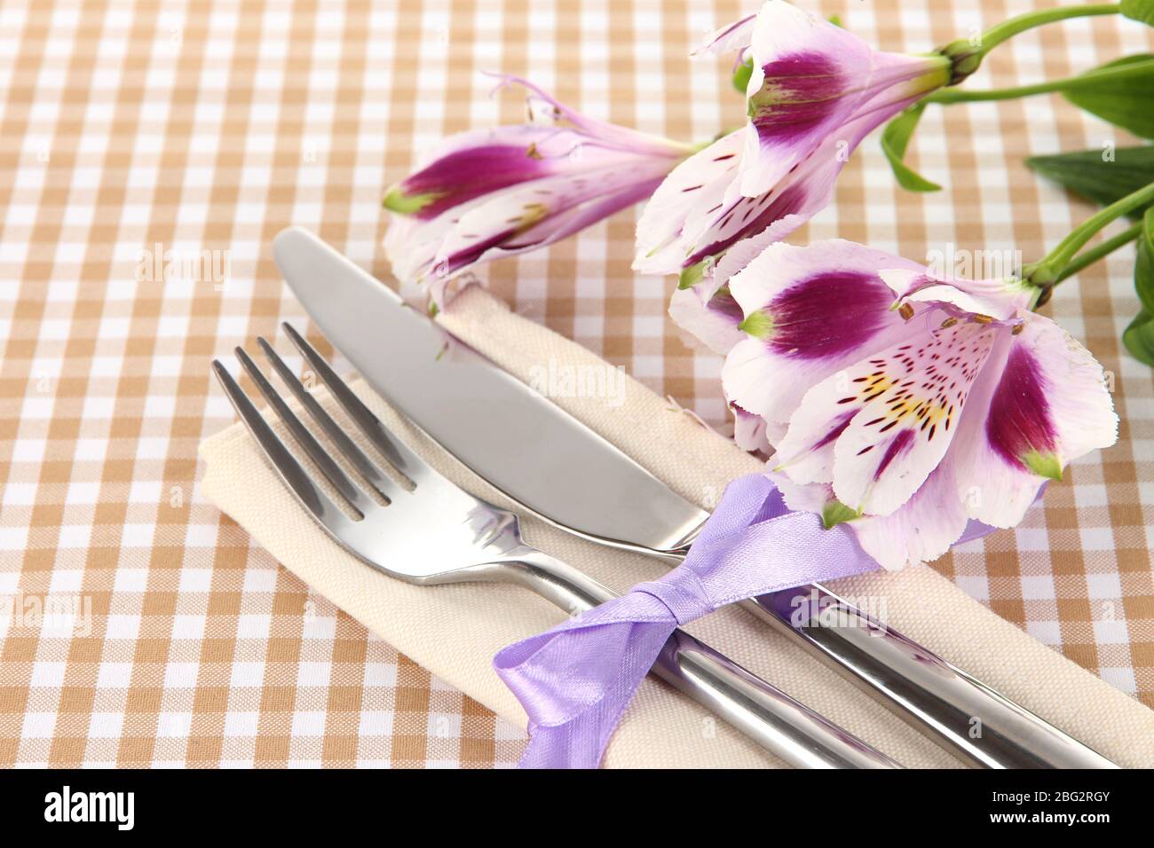 Tavolo da pranzo per le feste con fiori su sfondo a scacchi Foto Stock