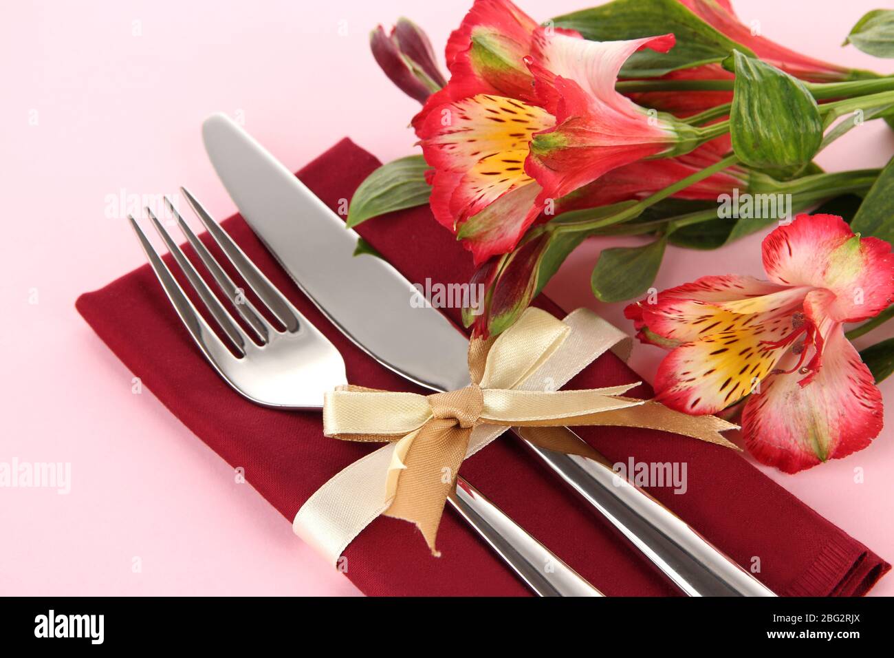 Tavolo da pranzo in festa con fiori su sfondo rosa Foto Stock
