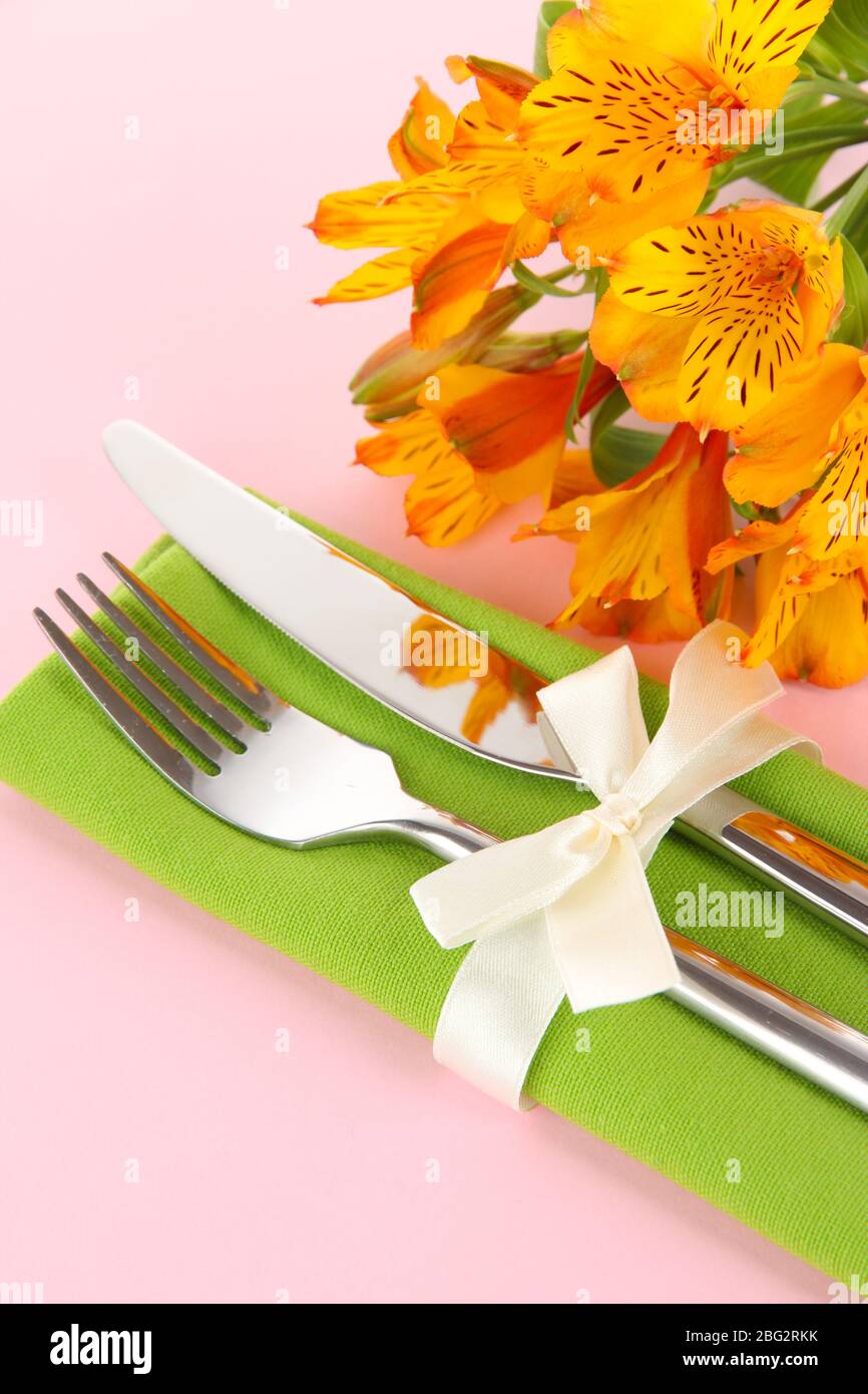 Tavolo da pranzo in festa con fiori su sfondo rosa Foto Stock