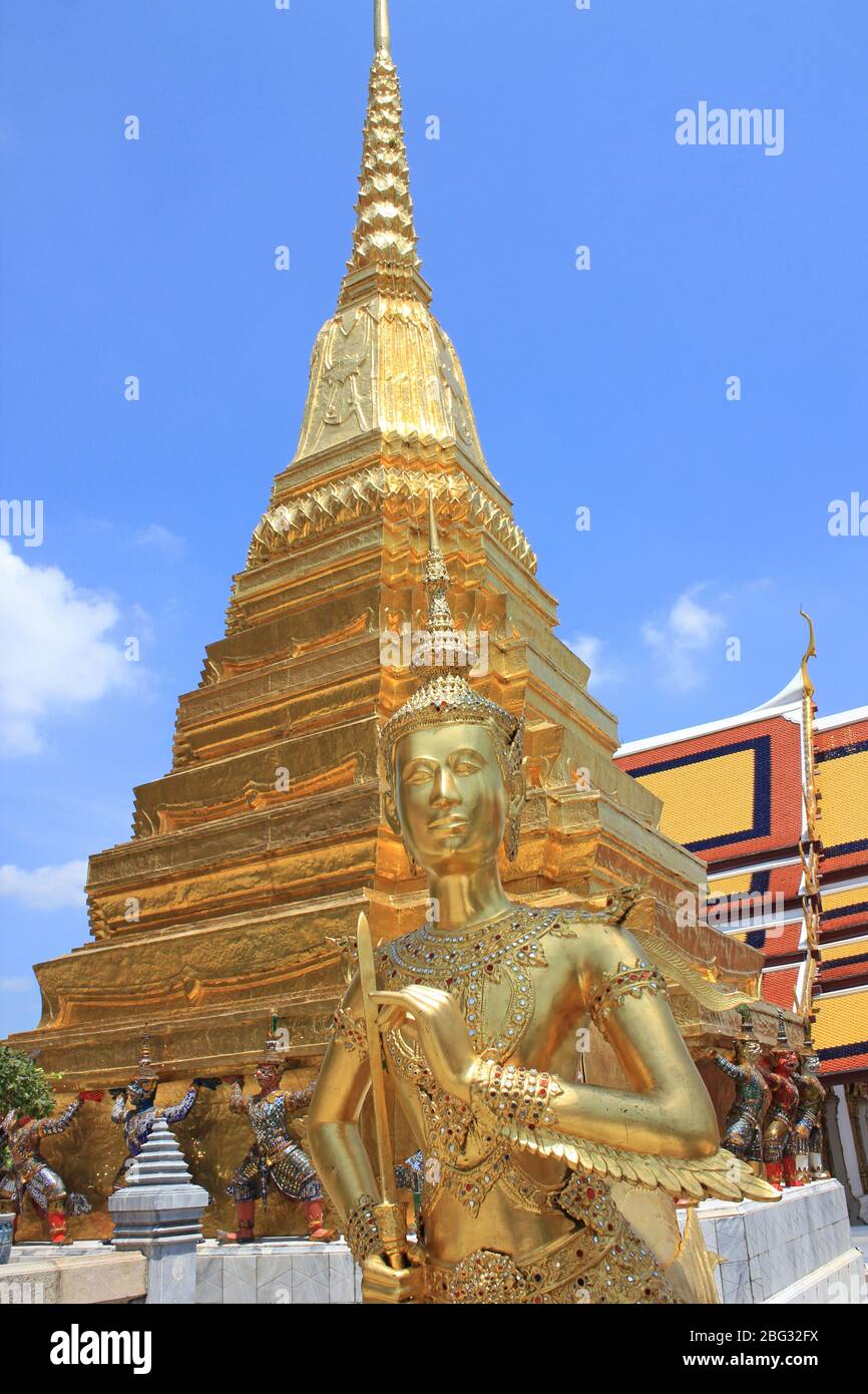 Statua di Kinnara (creatura mitologica, mezzo uccello, mezza donna) accanto al chedi d'oro a Wat Phra Kaew, Bangkok, Thailandia Foto Stock