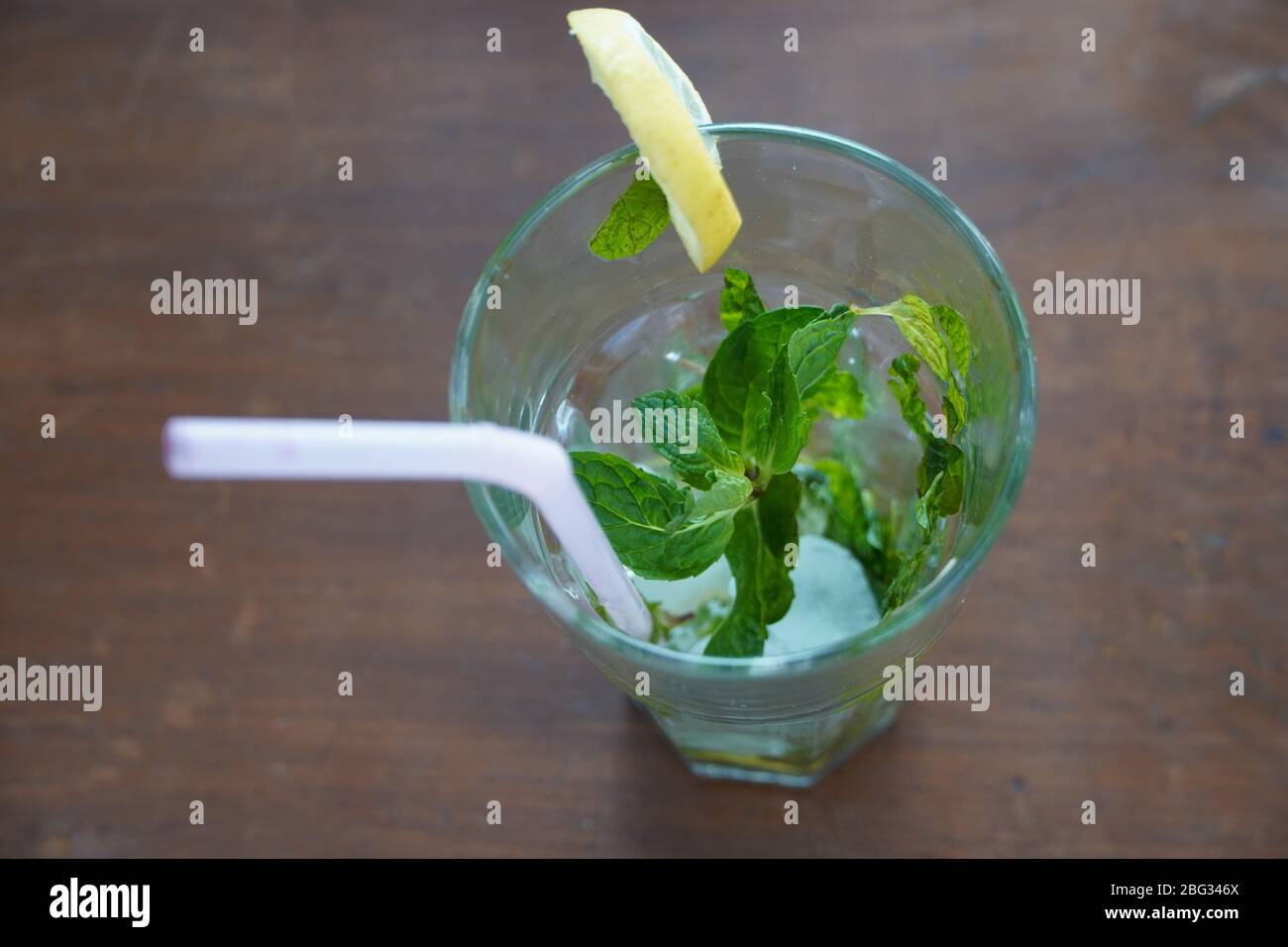 Vista dall'alto di un bicchiere vuoto con lime, menta, paglia e mojito di ghiaccio bere su un tavolo. Foto Stock