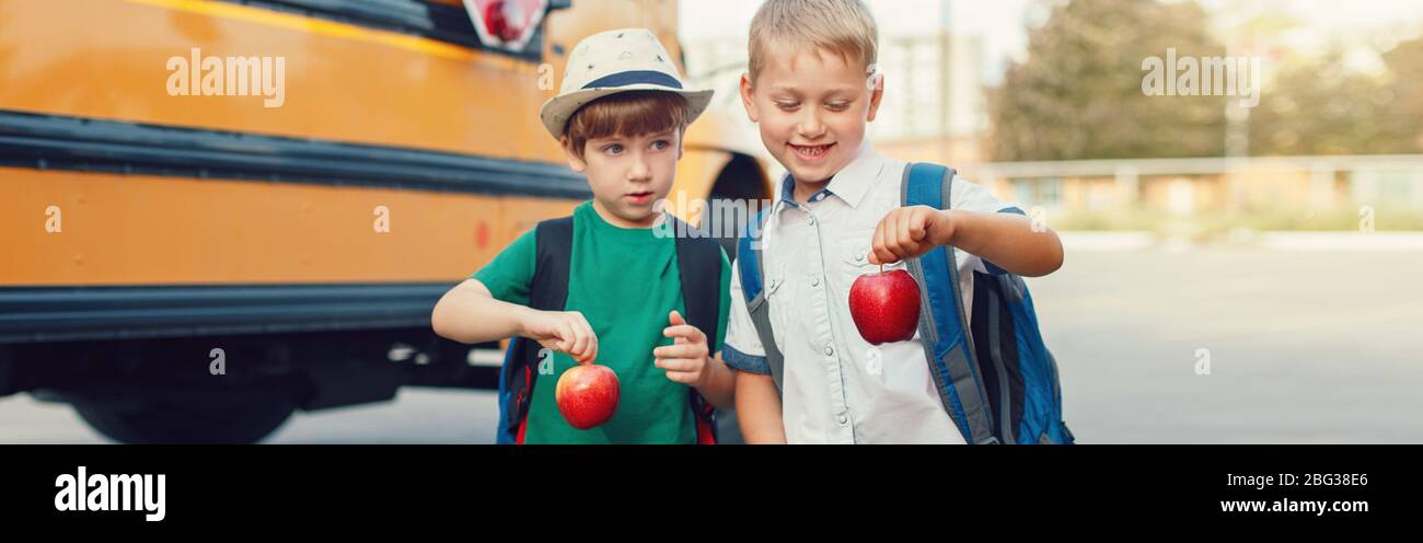 Due divertenti ragazzi caucasici ragazzi ragazzi ragazzi con mele in piedi su autobus giallo il 1 ° settembre giorno. Istruzione di nuovo a scuola. Bambini pronti per imparare Foto Stock