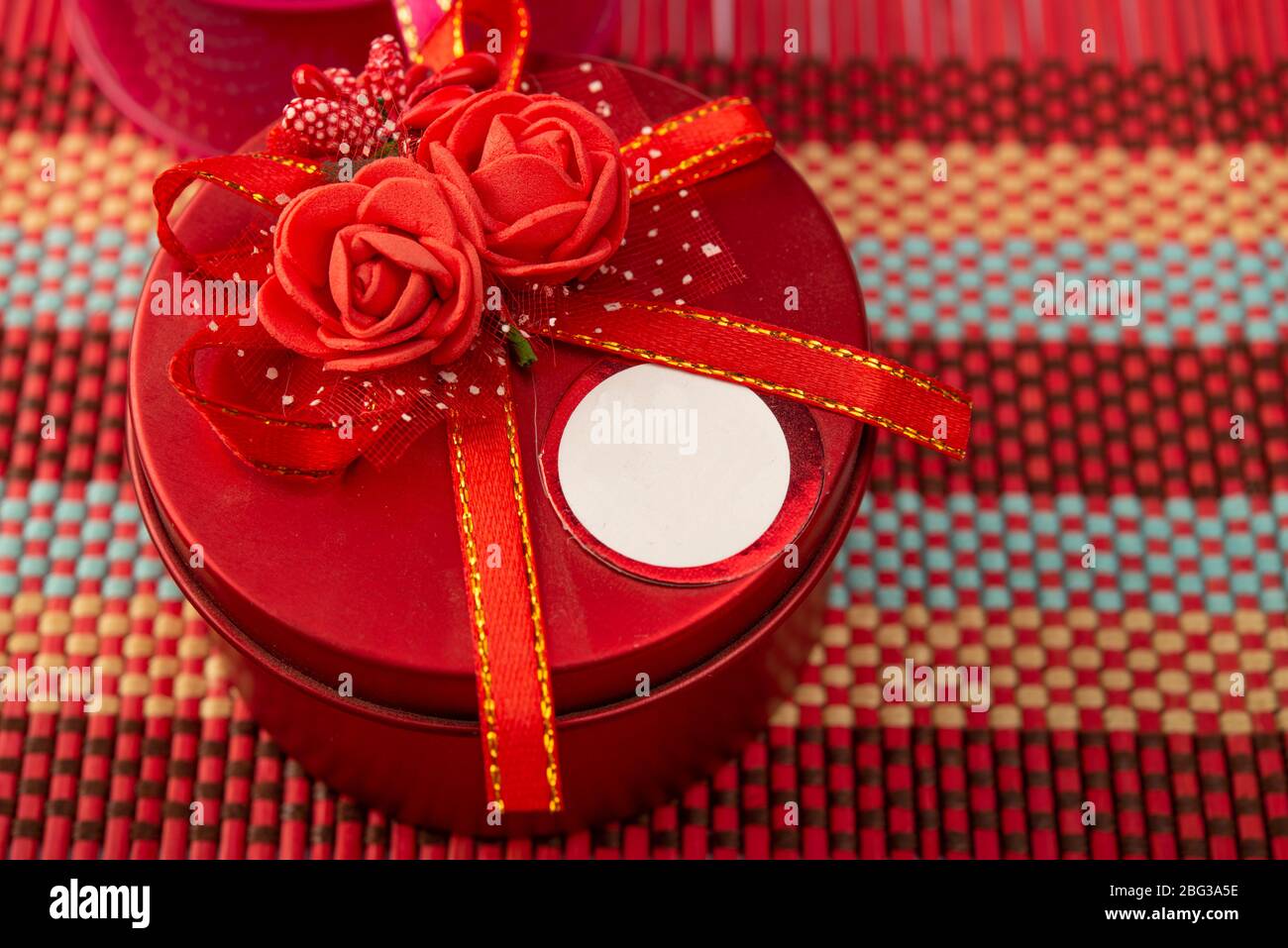 Primo piano di scatola regalo rossa con fiori in cima Foto Stock