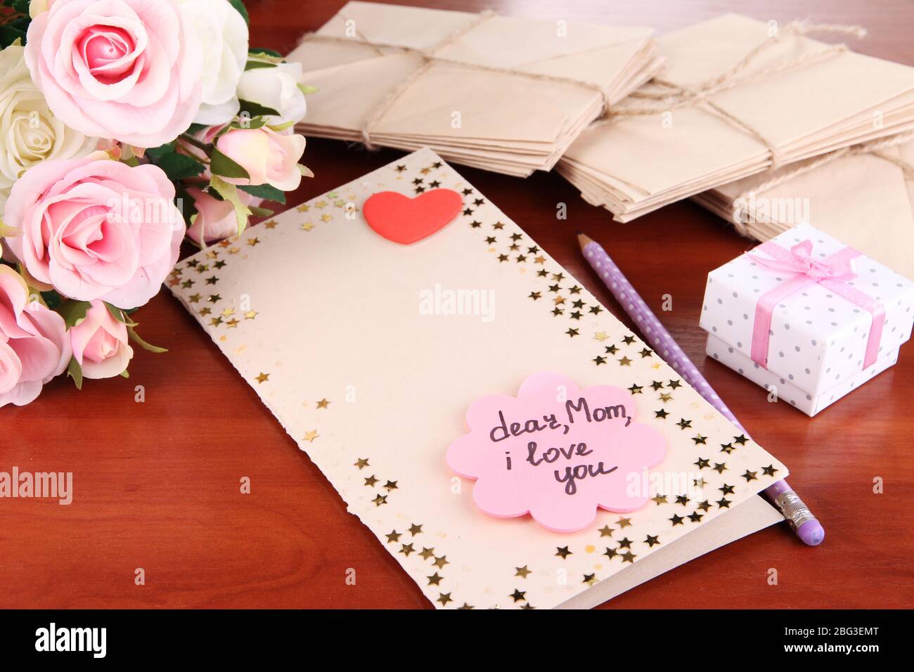 Lettera di congratulazioni per la festa della mamma sul tavolo in legno primo piano Foto Stock