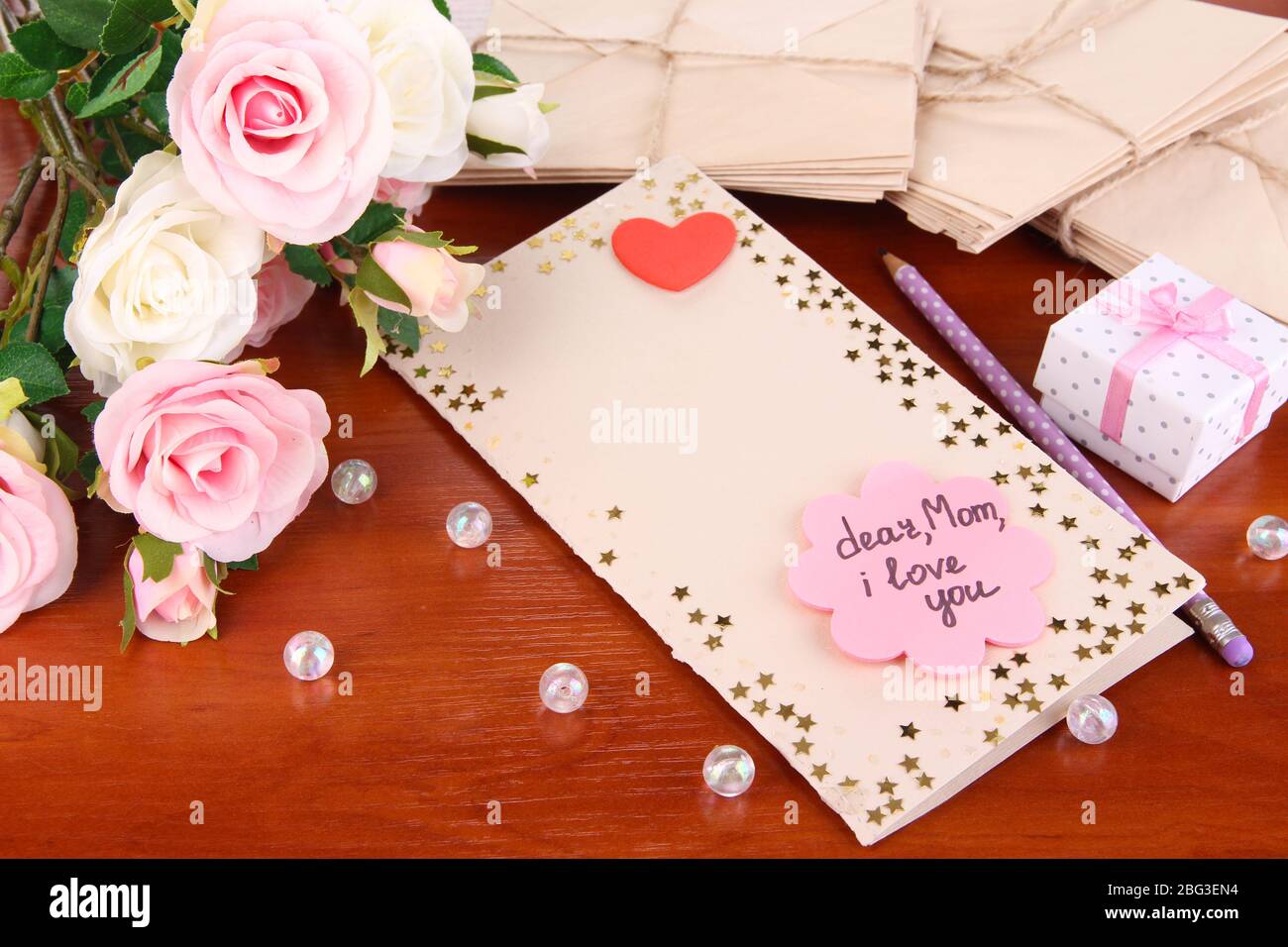 Lettera di congratulazioni per la festa della mamma sul tavolo in legno primo piano Foto Stock