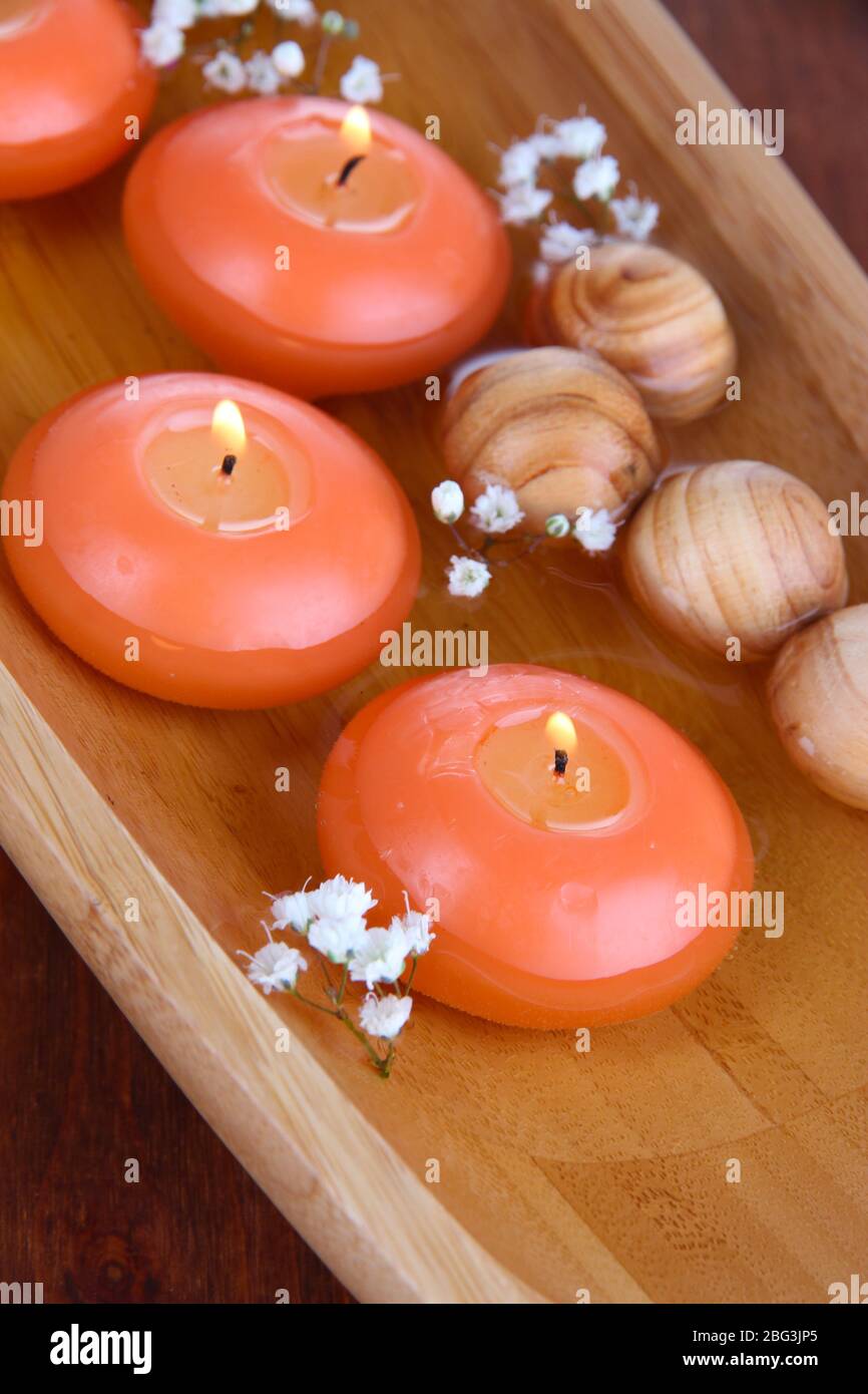 Belle candele in acqua su tavolo di legno primo piano Foto Stock