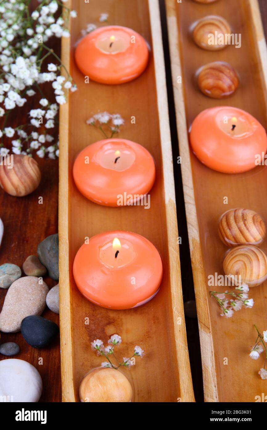 Belle candele in acqua su tavolo di legno primo piano Foto Stock
