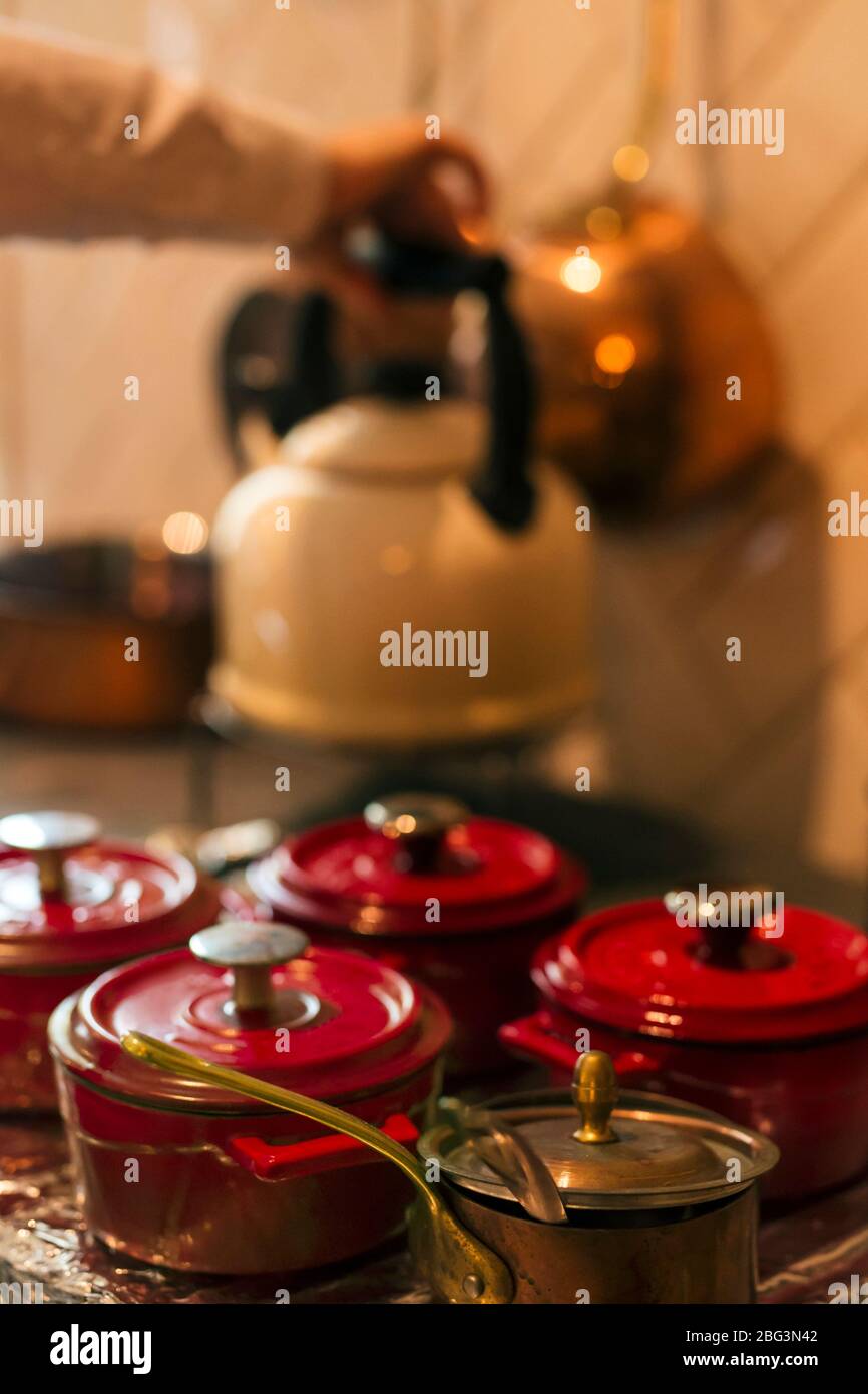 Mano umana mettere un bollitore su un piano di lavoro da cucina da piccole casseruole Foto Stock