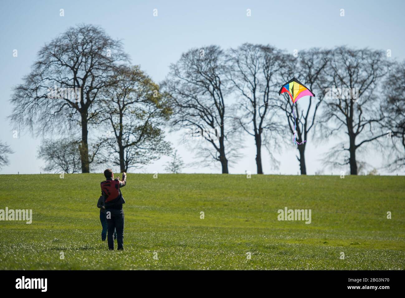 Bishopbriggs, Glasgow, Regno Unito. 20 aprile 2020. Nella foto: Rachel e Scott utilizzano il tempo di esercizio assegnato e approfittano di una bella giornata soleggiato e ventoso per volare il loro aquilone. Un cielo blu e un campo verde fanno da sfondo perfetto per il volo di aquiloni. Credit: Colin Fisher/Alamy Live News Foto Stock