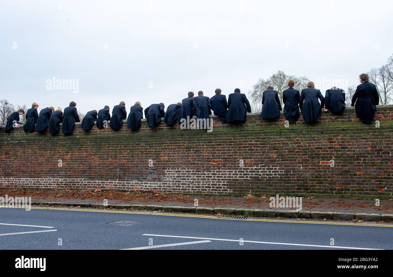 Eton, Windsor, Berkshire, Regno Unito. 20 novembre 2010. I ragazzi dell'Eton College si siedono in cima a un muro alto costruito nel 1717 accanto ai campi da gioco dell'Eton College mentre osservano i loro compagni di scuola competere nel Wall Game. Il primo gioco da parete registrato fu nel 1766. L'Eton College è una scuola pubblica a pagamento, frequentata da molti politici britannici, tra cui Boris Johnson e David Cameron. Anche il Principe William e il Principe Harry frequentarono l'Eton College. Credito: Maureen McLean/Alamy Foto Stock